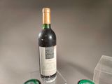 a bottle of wine sitting on a table next to some glasses