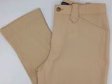 Le pantalon est de couleur beige et comporte des boutons sur les côtés.