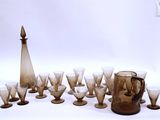 bottles and glasses are lined up in a circle on a white surface