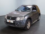 un SUV Suzuki gris garé dans une pièce au sol noir