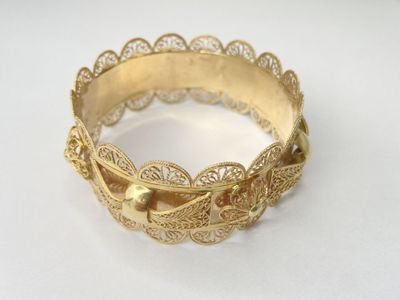 a close up of a gold bracelet on a white surface