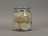 a glass jar filled with peeled bananas on a white surface