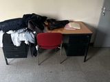 a desk with a red chair and a pile of clothes on it