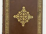 a brown book with gold trim and a cross on the cover