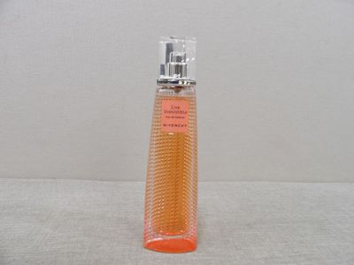 un flacon de parfum posé sur une surface blanche, avec un mur blanc en arrière-plan