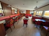 tables and chairs are lined up in a restaurant with red booths