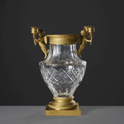 un vase plaqué or muni de deux anses et posé sur un socle