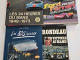 four books on a table with a picture of a race car in the background