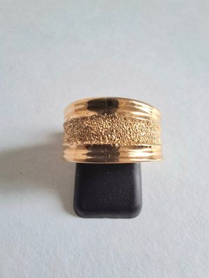 une photo d'une bague en or posée sur un socle noir