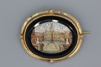 une photo d'une broche noire et dorée sur laquelle figure l'image d'un palais