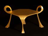 a gold chair that is sitting on a black surface
