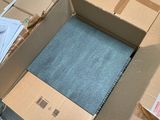 a box with a blue carpet on the floor next to a pile of boxes