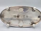 an antique silver plate with pearls on it sitting on a table