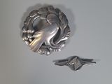 une broche en forme d'oiseau en argent et une bague en argent posées sur une table