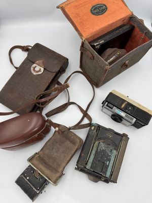 many different types of old cameras on a white surface
