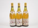 trois bouteilles de vin posées les unes à côté des autres sur une surface blanche