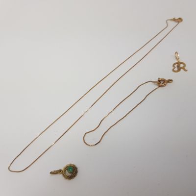 deux colliers en or ornés d'une pierre verte sur un fond blanc