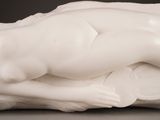 a white sculpture of a woman laying on a pillow