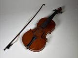 an old violin with a bow and bow rest on a white surface