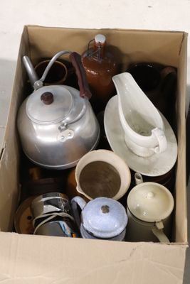 une boîte remplie de théières et de tasses posée par terre
