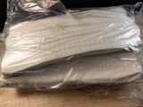 three pillows wrapped in plastic on a wooden table