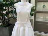 une robe blanche sur un mannequin, avec une plante en pot en arrière-plan