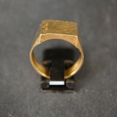 gros plan d'une bague en or sur une surface noire