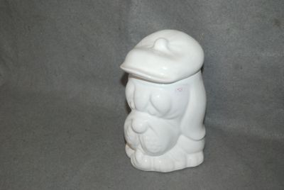 une figurine en céramique blanche représentant un ours coiffé d'un chapeau