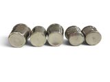 four silver metal knobs sitting on top of each other on a white surface