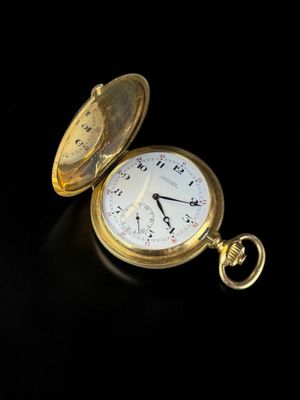 a gold pocket watch sitting on a black surface