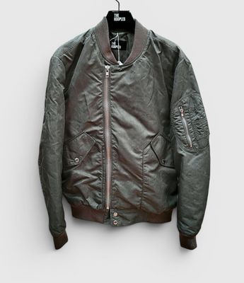 La veste bomber est suspendue à un cintre accroché au mur.