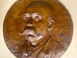 une plaque en bronze représentant un homme avec une pipe à la bouche