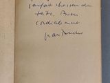 un livre ouvert, sur lequel est inscrit un poème écrit à la main, posé sur une table