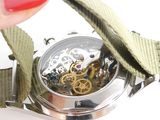 a person holding a watch with a green strap around it