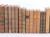 several old books are lined up in a row on a white surface