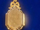a gold pendant with a picture on it on a blue surface