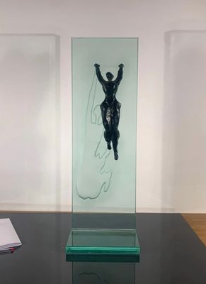 a glass sculpture of a man on a surfboard on a table