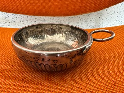 silver plated bowl with handle on orange cloth