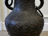 un grand vase noir posé par terre dans une pièce