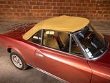 a red car with a yellow top parked in front of a brick wall