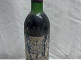 une vieille bouteille de vin posée sur une table blanche