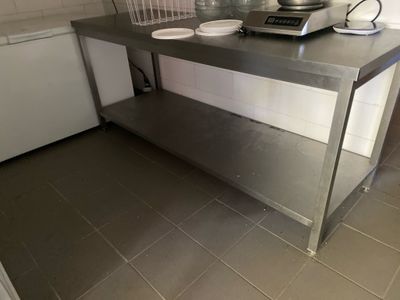 un plan de travail en acier inoxydable dans une cuisine équipée d'une cuisinière et d'un lave-vaisselle