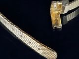 two pieces of silver and gold bracelets on a black surface