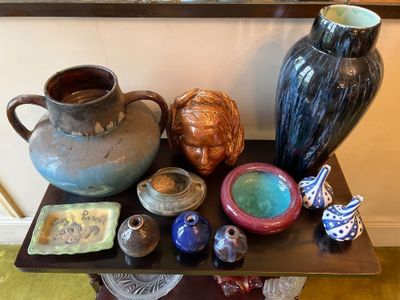 de nombreux vases et bols posés sur une table, avec un miroir en arrière-plan