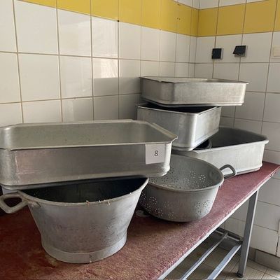 Plusieurs casseroles sont alignées sur une table dans une cuisine