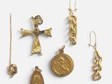 plusieurs bijoux en or, dont une croix, une médaille et une pièce de monnaie