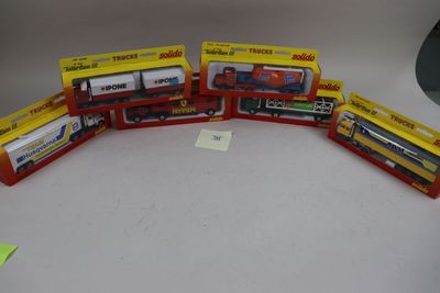 trois trains miniatures dans leurs boîtes, posés les uns à côté des autres sur une table