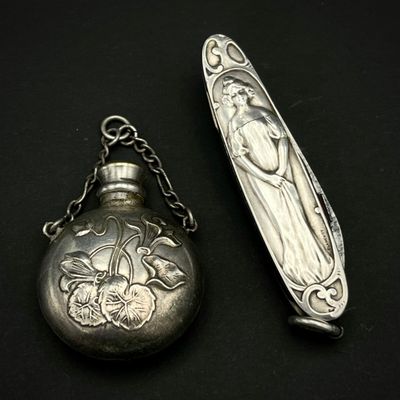 une cuillère en argent et une montre de poche en argent posées sur une surface noire