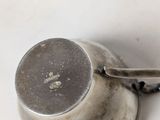 a silver cup with a handle on a white table