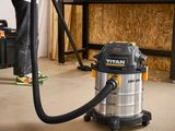 the man is using a vacuum to clean the floor in the garage